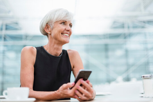 Smiling senior woman with cell phone in a cafe