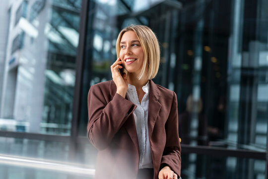 Smiling young businesswoman on the phone in the city