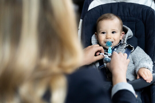 Portrait of baby boy with pacifier in strollerwatching his mother