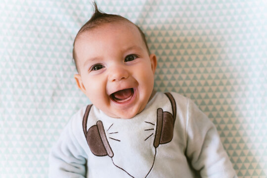 Portrait of laughing baby girl with appliqued headphones on pyjama
