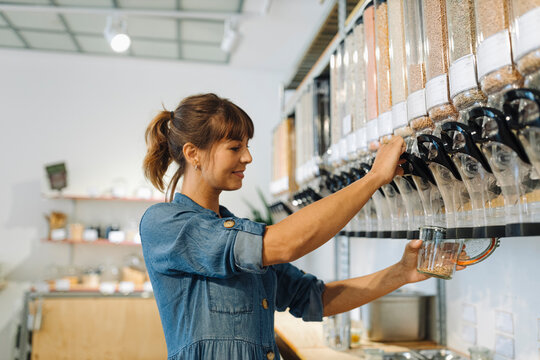 Young female owner removing food from jar while standing in cafe