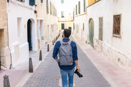 Back view of man with camera exploring the city, Mao, Menorca, Spain