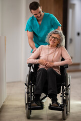 Fototapeta premium Nurse pushing happy senior woman in wheelchair