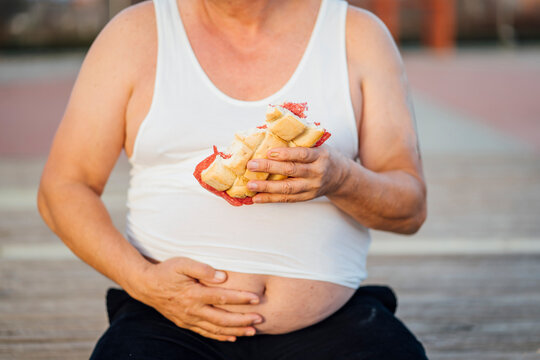 Man with beer belly holding sandwich
