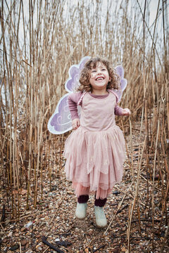 Portrait of happy little girl in nature dressed up as a butterfly