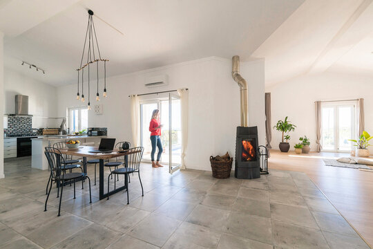 Woman standing in door frame of modern living room with fireplace