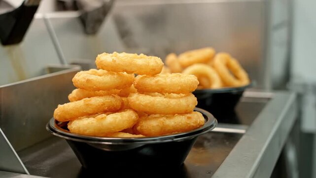 Close-up of Delicious Golden Onion Rings Served in Black Bowls, Freshly Fried and Ready to Eat