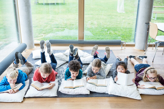 Students relaxing on the floor with books during their school break in the reading room