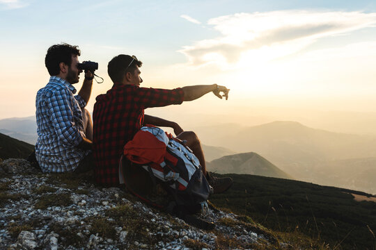 Italy, Monte Nerone, two hikers on top of a mountain enjoying the view at sunset