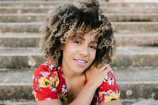 Trendy young woman sitting on steps during sunny day