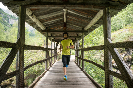 Italy, Alagna, man running on wooden bridge in the mountains