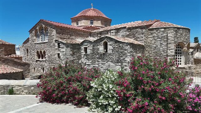 Paros Island,Aerial view tilt up from colorful oleanders to Ekatontapyliani Church,Holy Shrine of Virgin Mary on a sunny day. Beautiful historical architecture.
