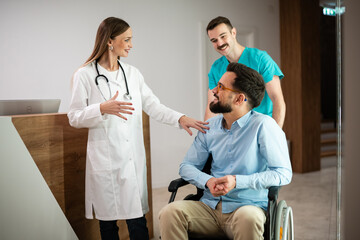Medical team assisting patient in wheelchair at clinic