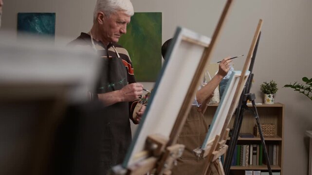 Senior people painting together while enjoying wine in art studio during creative class, promoting social connection and active aging