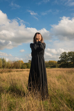 art portrait of woman in black classic dress in field veiled in autumn light