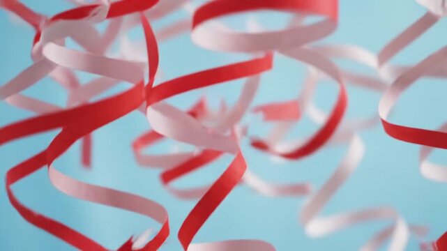Festive striped peppermint candy canes arranged in a glass and shaped like a sweet heart on a red background decorated with a Christmas ribbon bow for a holiday celebration