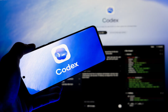 Hand holding smartphone displaying Codex AI logo on screen with blurred code editor background, concept for artificial intelligence in software development and programming