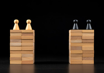 Two opposing towers constructed from wooden blocks with contrasting colored game pieces at the top