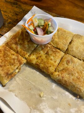 Traditional Thai-Muslim Beef Mataba or Stuffed Crispy Roti served with cucumber relish on a white plate.