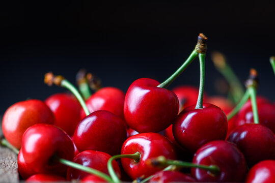 Fresh cherries filling the frame, dark moody lighting. Ripe sweet red fruit texture, summer food background