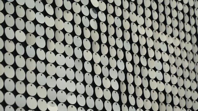 Reflective circular pattern. Metallic, reflective, circular discs, sequins or reflective panels, arranged in a grid pattern on the facade of a modern building. High quality 4k footage