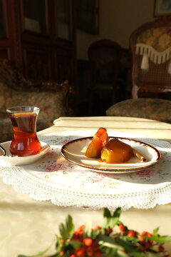 Authentic candied pumpkin dessert served with traditional Turkish black tea, red berries, and cinnamon on a vintage marble table with beautiful golden hour light and bokeh.