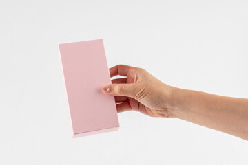 Obraz premium A small pink gift wrapping box and hand against a white background.