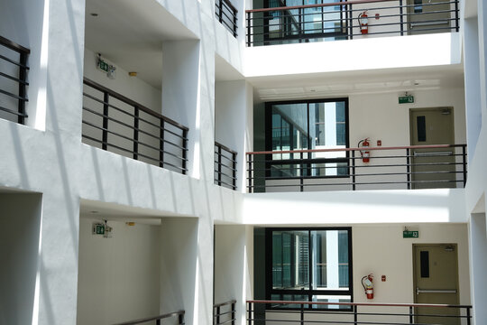 Modern architectural design featuring multiple levels of a building with balconies, large windows, and natural light illuminating the interior space