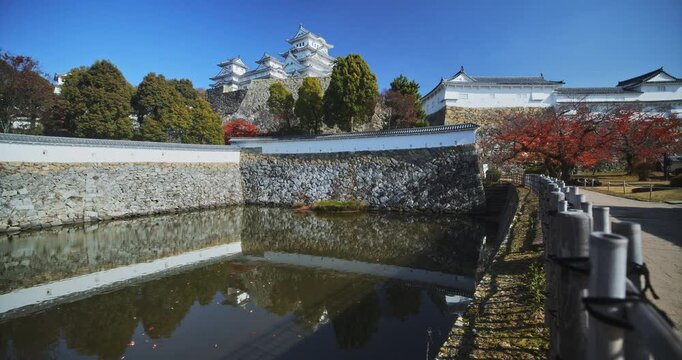 Still pond in front of stone wall with distant Matsumoto castle - wide shot