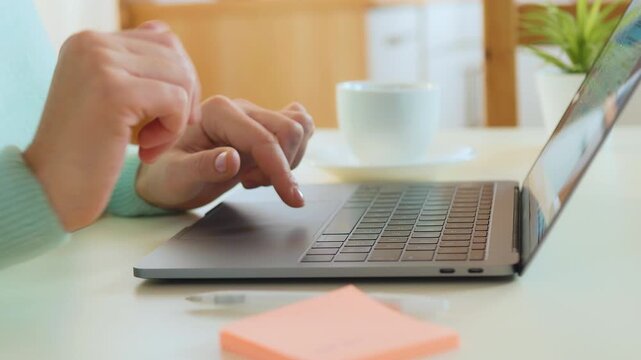 A person uses a smartphone for contactless payment near a laptop, indicating online shopping or banking in a modern workspace. The scene emphasizes digital transactions and financial activities.