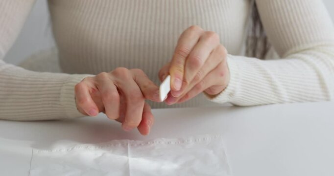 Closeup of a woman's hands using a nail file for a manicure at a white table