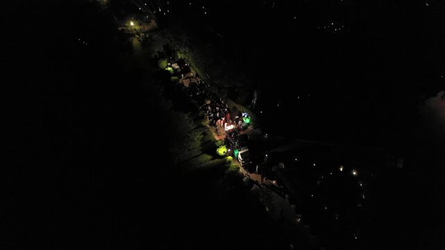 Aerial night shot of a traditional Indian wedding baraat with decorated car, dancers, and festive lights in india