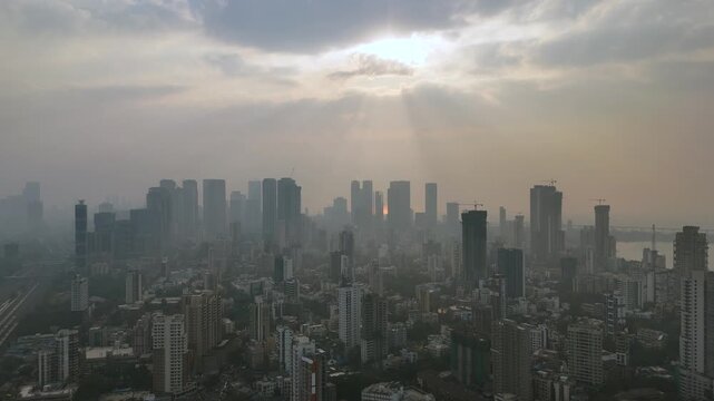 Aerial skyline of Mumbai city at sunrise with dramatic sun rays and dense urban high-rises