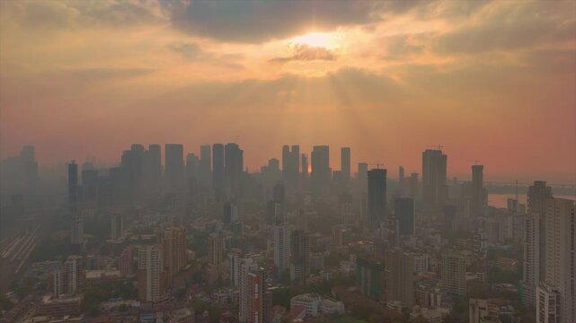 Aerial skyline of Mumbai city at sunrise with dramatic sun rays and dense urban high-rises