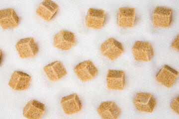 Brown sugar cubes on white sugar background. Top view. Flat lay.