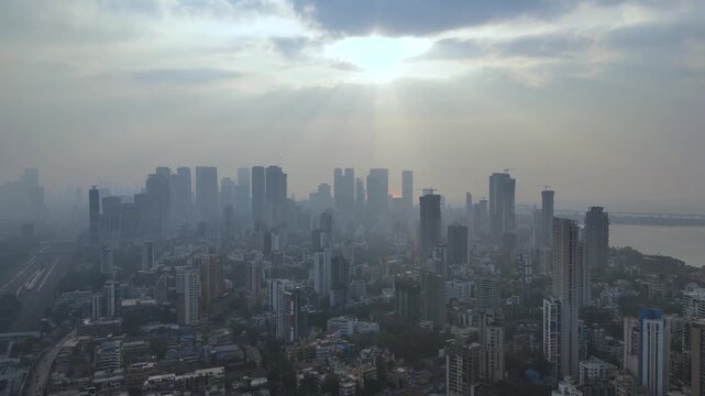 Aerial skyline of Mumbai city at sunrise with dramatic sun rays and dense urban high-rises