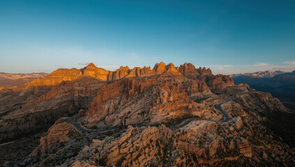 Serpentine mountain pass winding through red rock canyon at golden hour with dramatic light