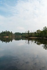 Fototapeta premium Clear water reflection: perfectly mirrored landscape in still lake, symmetrical composition, serene minimalist nature.