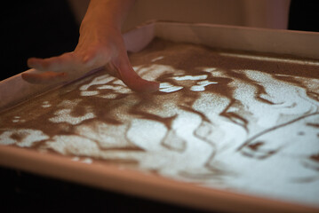 Fingers Shaping Detailed Sand Art Composition With Soft Light