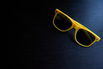 Bright yellow sunglasses on dark wooden table