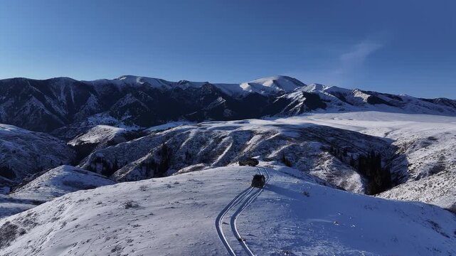 Off-road vehicle driving on a snowy Dzungarian Alatau mountain ridge top