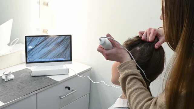 Trichologist examining scalp with digital dermatoscope, close up of hair and skin analysis on screen. Woman specialist performing hair diagnostics procedure in modern clinic, medical consultation conc