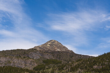 Scenic landscape of majestic rocky mountain peak under blue sky with wispy clouds in rural countryside of Norway Scandinavia Europe