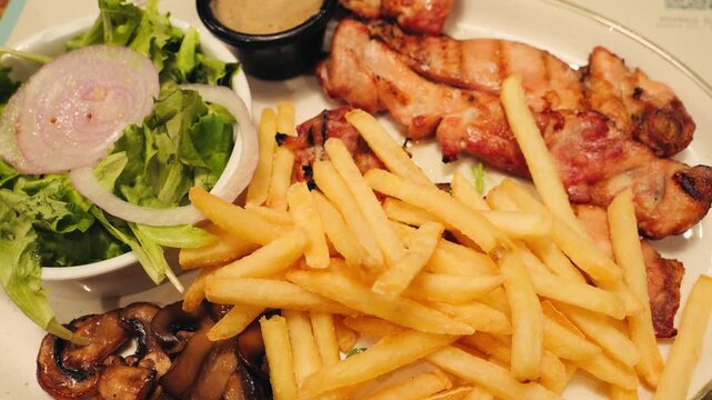 Close up of grilled chicken with special sauce, french fries, grilled mushrooms and salad on plate. High quality 4k footage