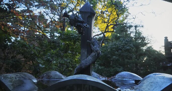 Silhouette of water dripping from mouth of dragon statue fountain in autumn area
