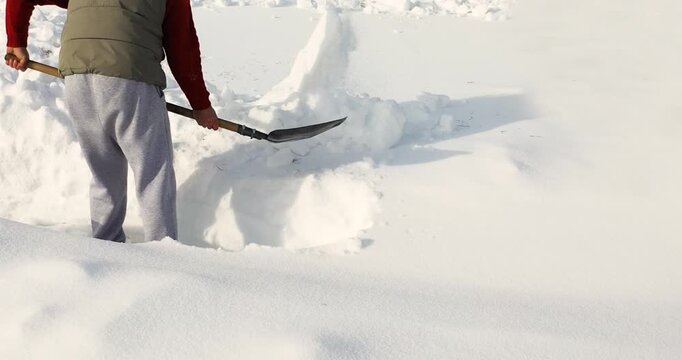 A determined man makes slow, methodical progress carving a path through heavy snow, emphasizing patience, strength, and persistence in this demanding winter setting. 30 FPS 4k footage.