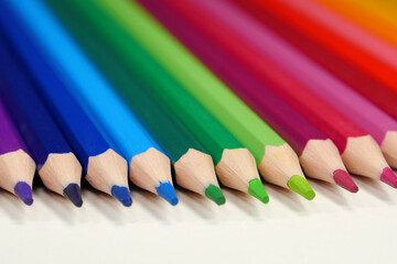 New wooden colored pencils of rainbow colors, perfectly sharpened, lie on table
