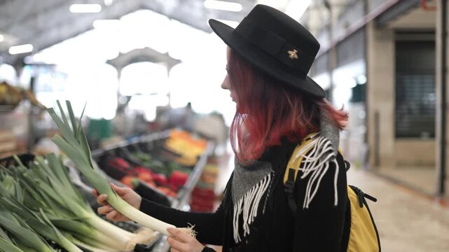 Young woman choosing fresh leeks at greengrocer's market