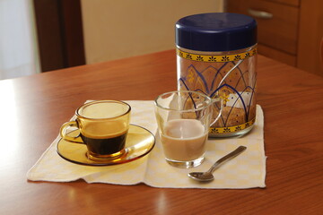 Espresso coffee cup, milk, and sugar on kitchen table