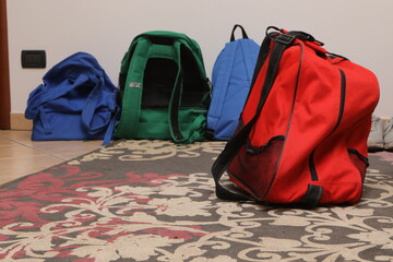 Colorful backpacks and bags waiting on patterned rug